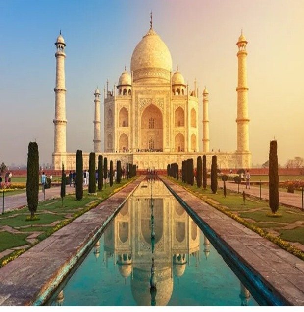 The Taj Mahal reflected in its garden pool at sunrise